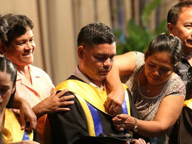 Saint Theresa's College confidence ensure Erwin Macua graduates with a bachelor's grade in Elementary Education. He receives his hood from his mom and his top from his mom Irenea during a graduation rites. PHOTO: FACEBOOK around CEBU DAILY NEWS 