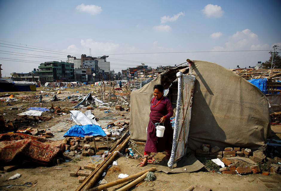 A woman carrying her belongings walks out from the makeshift shelter before it was demolished at the displacement camp for earthquake victims at Chuchepati in Kathmandu, Nepal. PHOTO: AFP