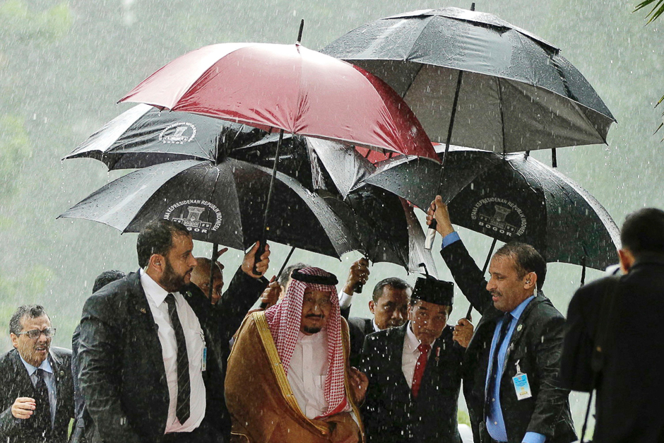 Saudi Arabia's King Salman bin Abdul Aziz (centre L) and Indonesia's President Joko Widodo (centre R) walk in heavy rain at the presidential palace in Bogor, West Java. PHOTO: REUTERS