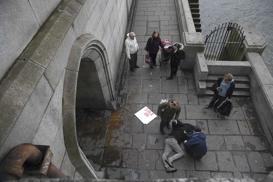 An injured man is assisted on the footpath under Westminster Bridge after the incident. PHOTO: REUTERS