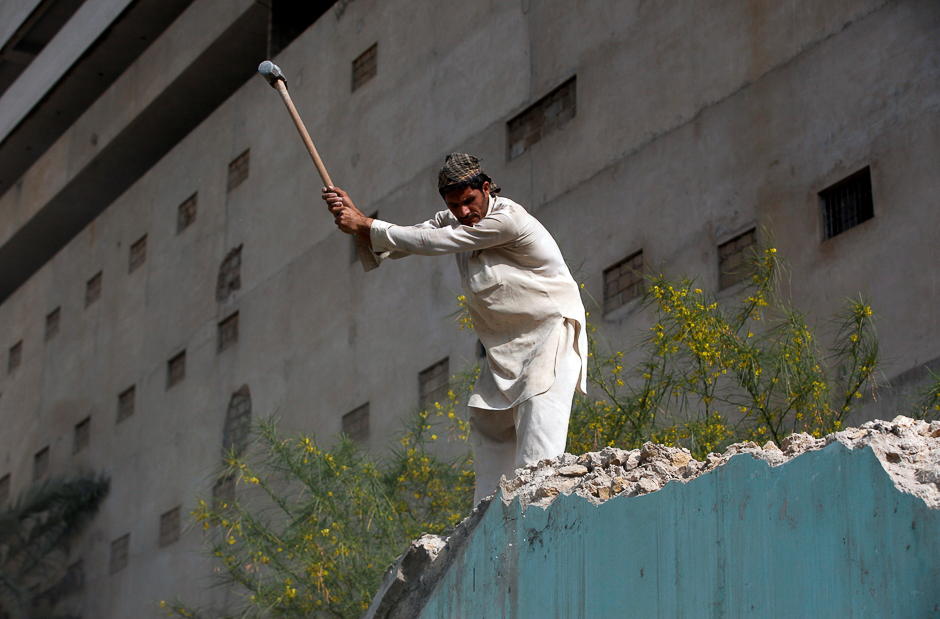 Taj Mohammad, 32, a labourer, uses a sledge hammer to remove an old wall near a newly constructed building in Karachi, Pakistan. PHOTO: REUTERS