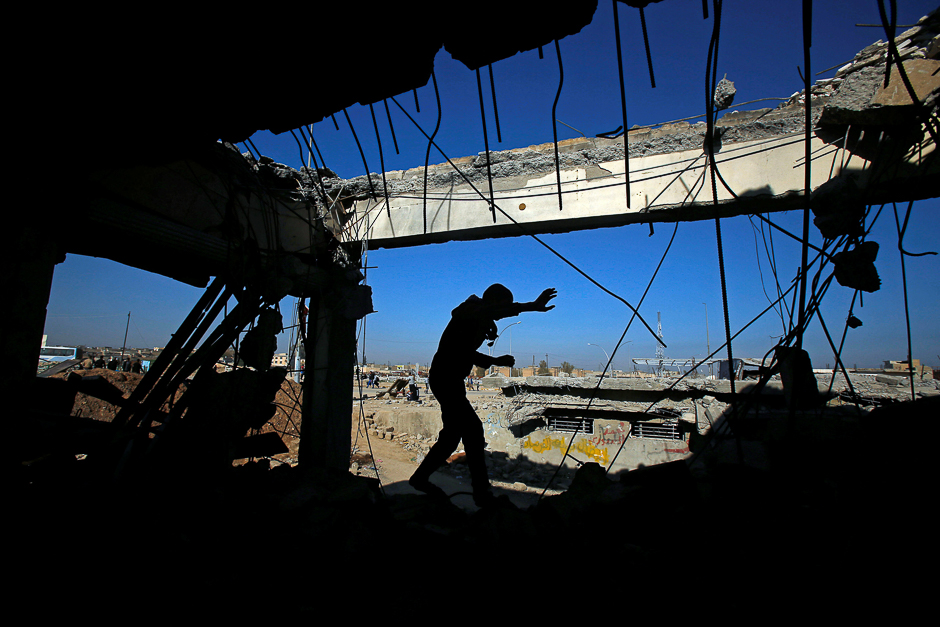 An Iraqi runs through a destroyed building as Iraqi forces battle with Islamic State militants, in the Somod neighbourhood in western Mosul, Iraq. PHOTO: REUTERS