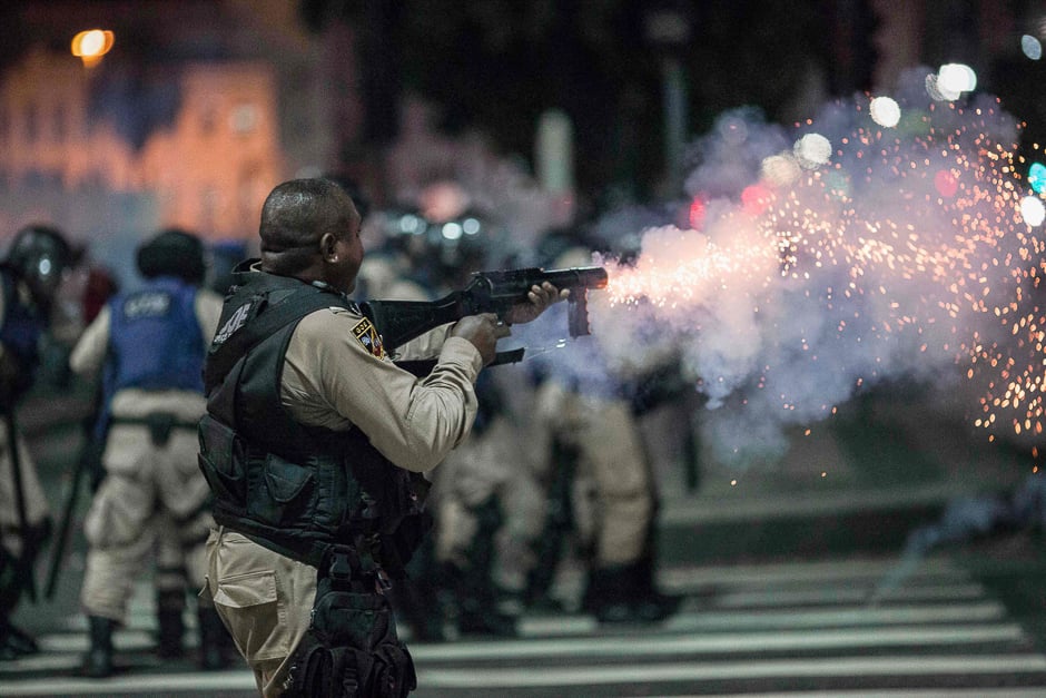 A municipal guard in riot gear fires rubber bullets at protestersâ during a national strike against the government's social welfare reform bill which seeks to extend the time of contributions and raise the minimum age required to obtain full retirement benefits, in Rio de Janeiro, Brazil. PHOTO: AFP