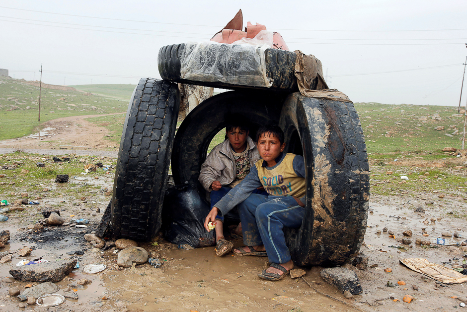 Displaced Iraqi people shelter from the rain on the street near the city of Mosul, Iraq. PHOTO: REUTERS