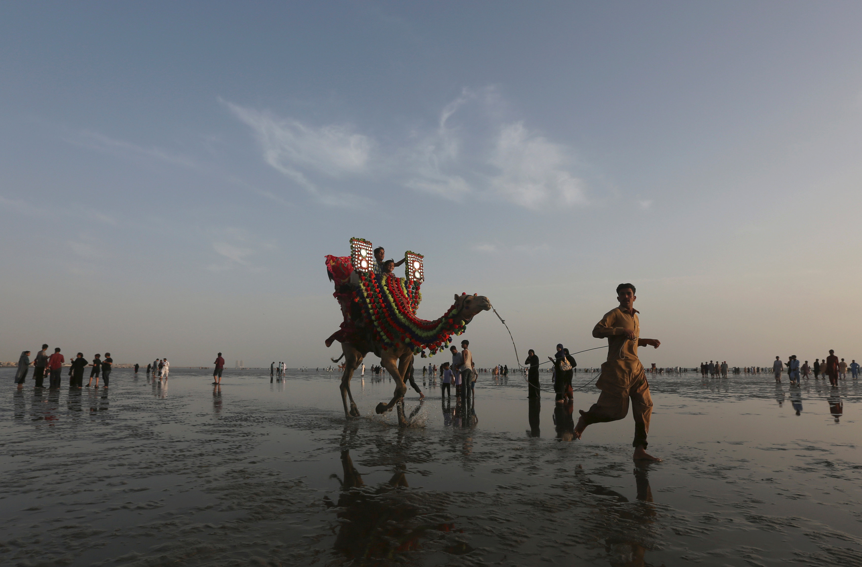 A man leads a camel with children taking a ride on it along the Clifton beach in Karachi, Pakistan March 12, 2017. REUTERS/Akhtar Soomro