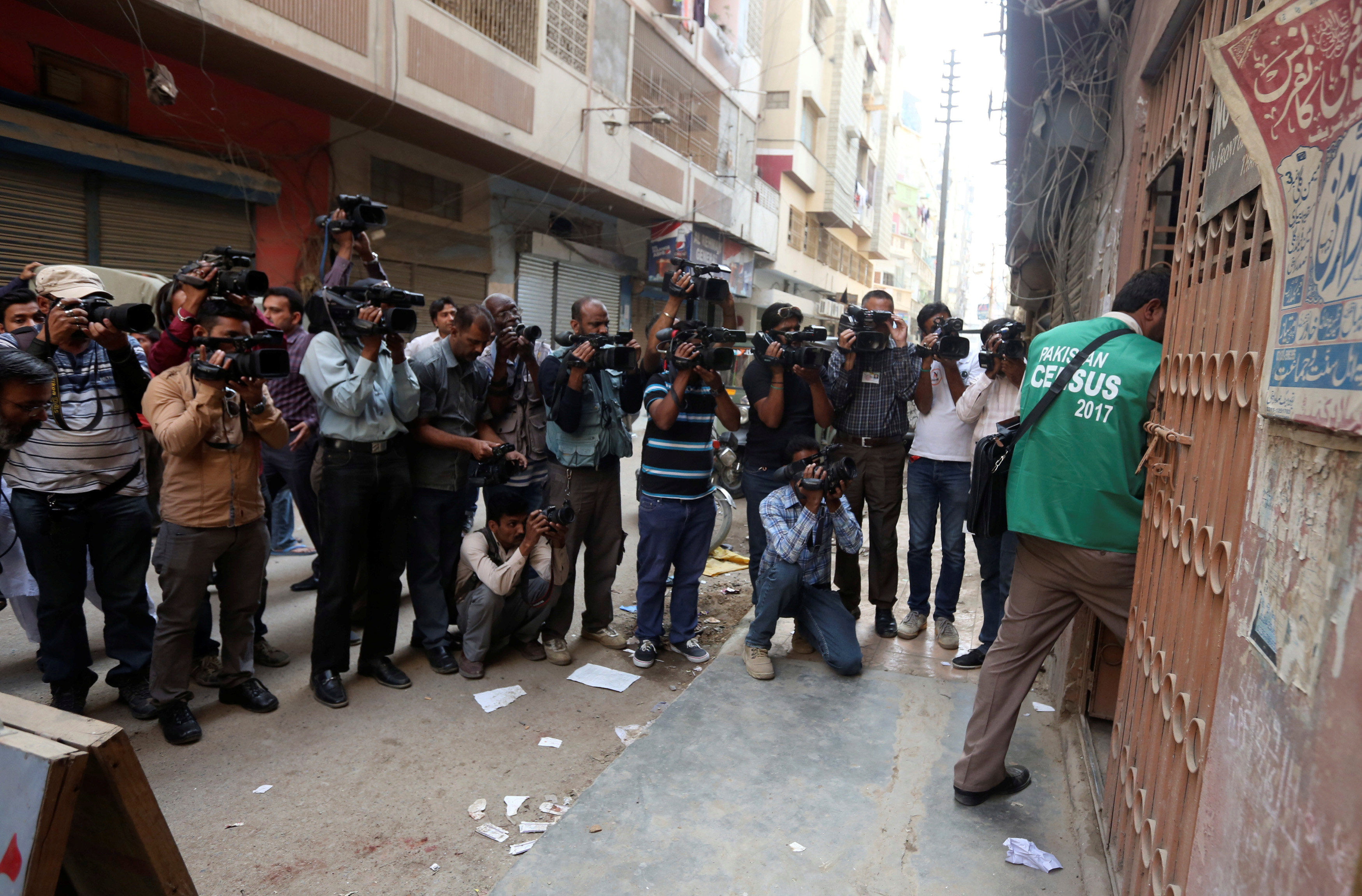 Cameramen and photographers document as a census enumerator (R) enters in a building during Pakistanâs 6th population census in Karachi. PHOTO: REUTERS