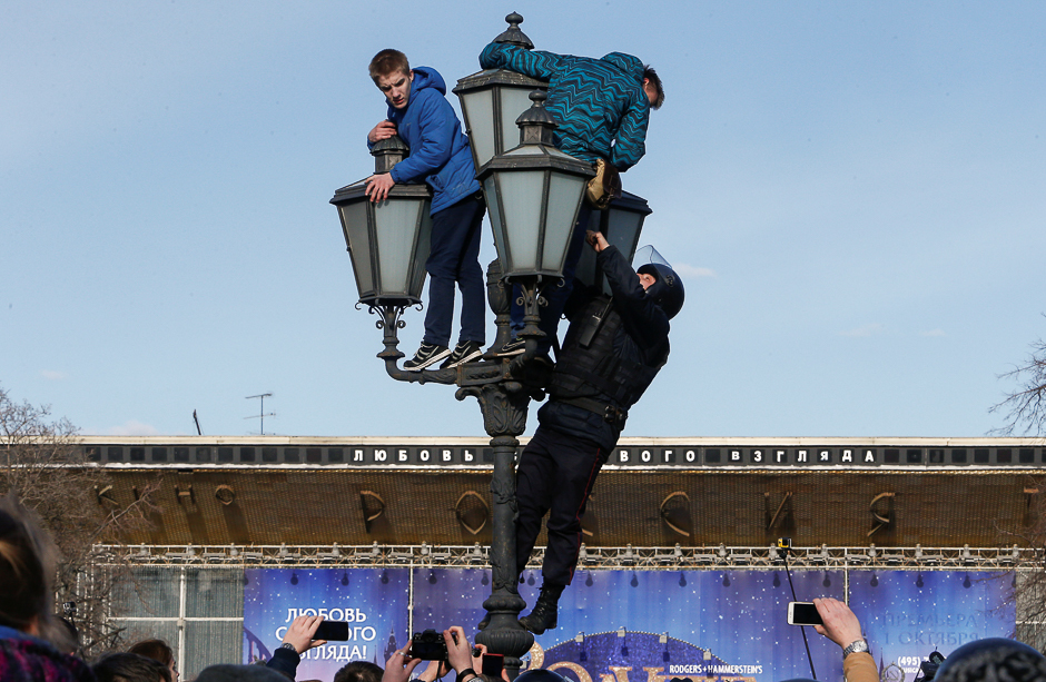 A law enforcement officer climbs on a lamp pole to detain opposition supporters during a rally in Moscow, Russia. PHOTO: REUTERS