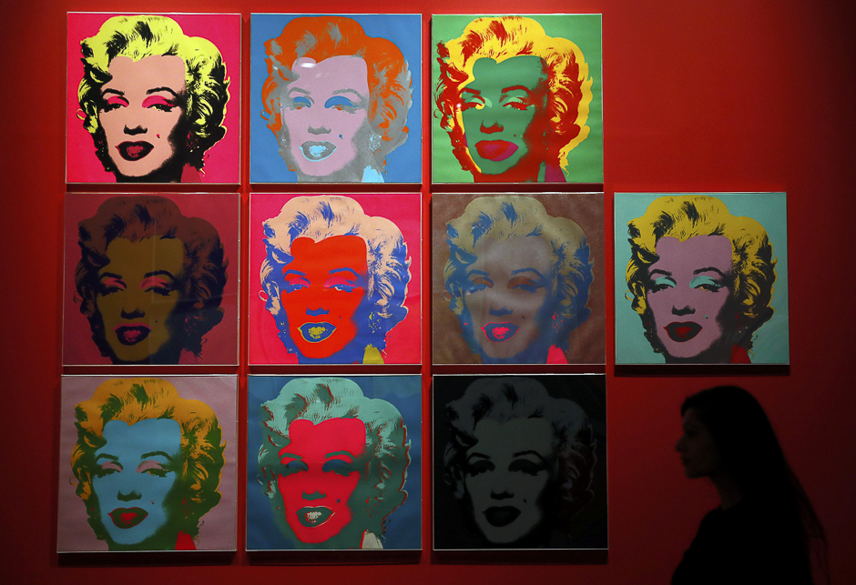 An employee poses with ten screenprints of Marilyn Monroe by Andy Warhol at the exhibition 