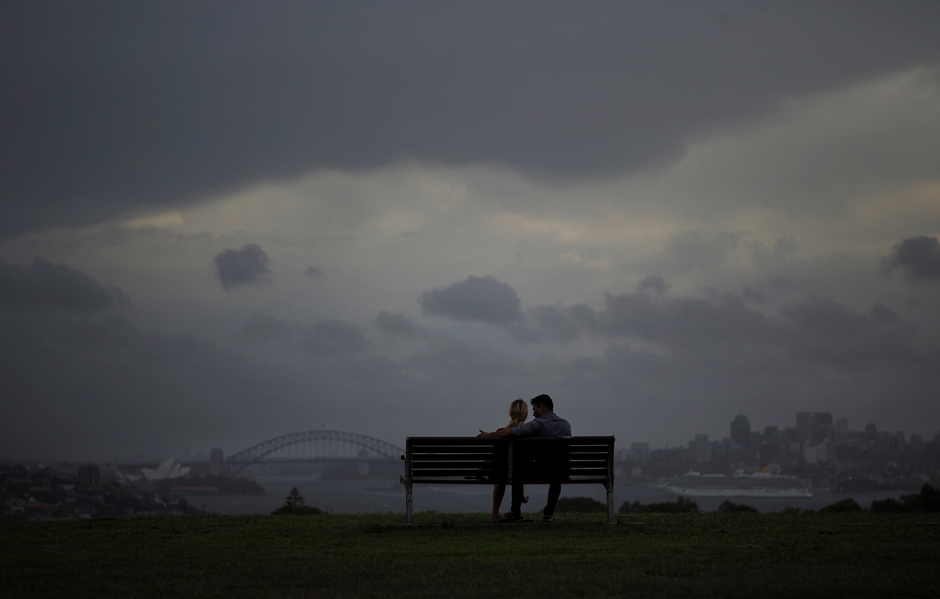 A couple observe a rain storm over Sydney, Australia, as a supercell hits Australia's most populous city. PHOTO: REUTERS
