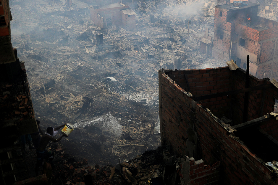 A resident pours water from his house as he tries to extinguish a fire at Paraisopolis slum in Sao Paulo, Brazil. PHOTO: REUTERS