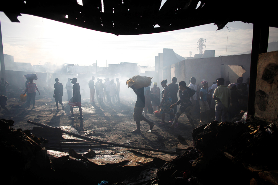 Haitians walk in the remains of a fire in a market in Port-au-Prince, Haiti. PHOTO: REUTERS