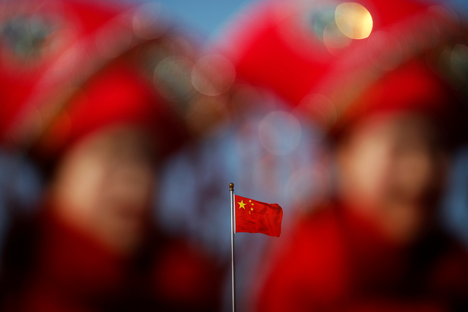 China's national flag is seen behind hostesses waiting for delegates outside the Great Hall of the People during the second plenary session of the National People's Congress (NPC) in Beijing, China. PHOTO: REUTERS