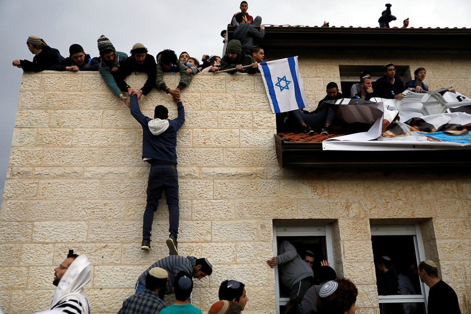 A pro-settlement activist climbs onto a rooftop of a house to resist evacuation of some houses in the settlement of Ofra in the occupied West Bank, during an operation by Israeli forces to evict the houses. PHOTO: REUTERS
