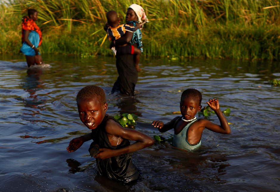 Children cross a body of water to reach a registration area prior to a food distribution carried out by the United Nations World Food Programme (WFP) in Thonyor, Leer county, South Sudan. PHOTO: REUTERS