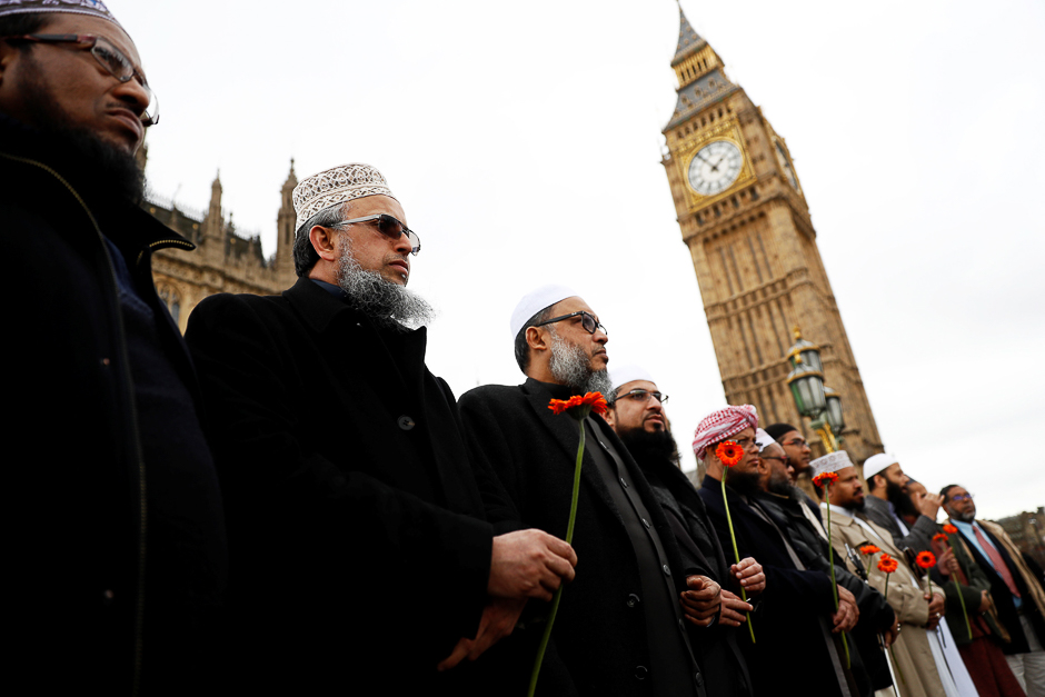 Muslim men hold flowers as they stand in line on Westminster Bridge during an event to mark one week since a man drove his car into pedestrians then stabbed a police officer in London, Britain. PHOTO: REUTERS