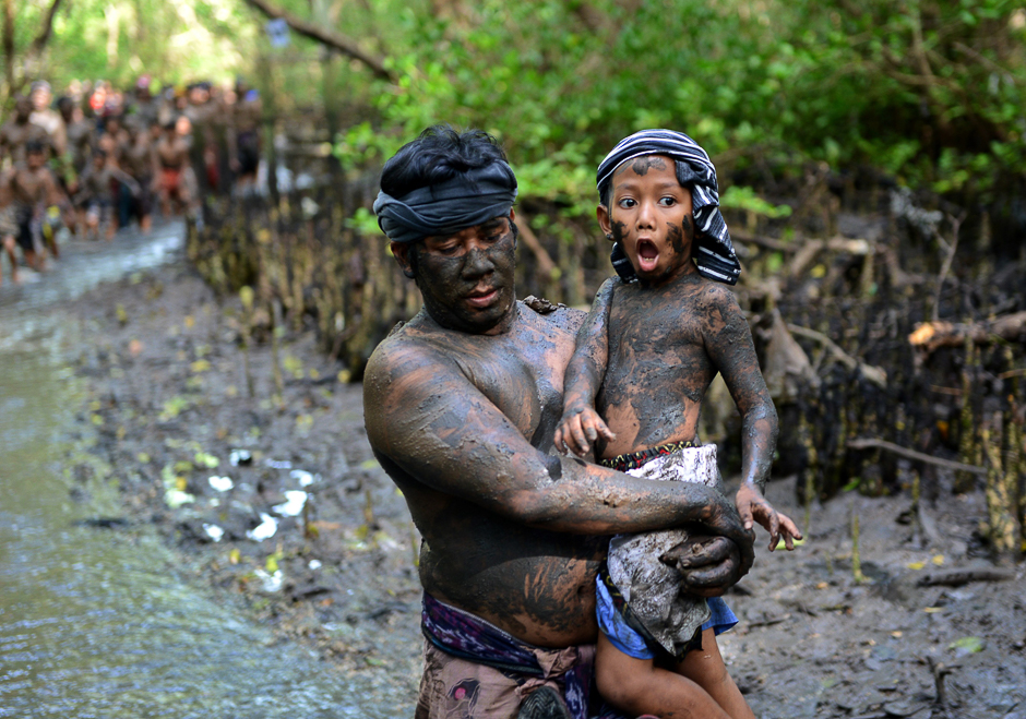 Balinese man holds his son after putting mud on their body during a mud bath tradition known as Mebuug-buugan, in Kedonganan village, near Denpasar on Indonesia's resort island of Bali. PHOTO: AFP