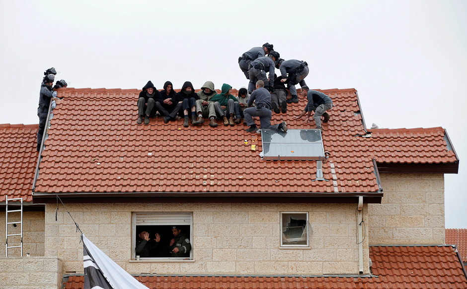 Israeli policemen remove pro-settlement activists from a rooftop as Israeli forces carry out a court order to demolish nine houses built illegally on privately owned Palestinian land, in the Israeli settlement of Ofra, in the occupied West Bank. PHOTO: REUTERS