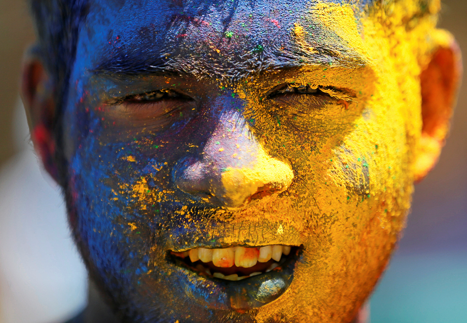 A boy with his face smeared in coloured powder, is seen during Holi, the Festival of Colours organised by 
