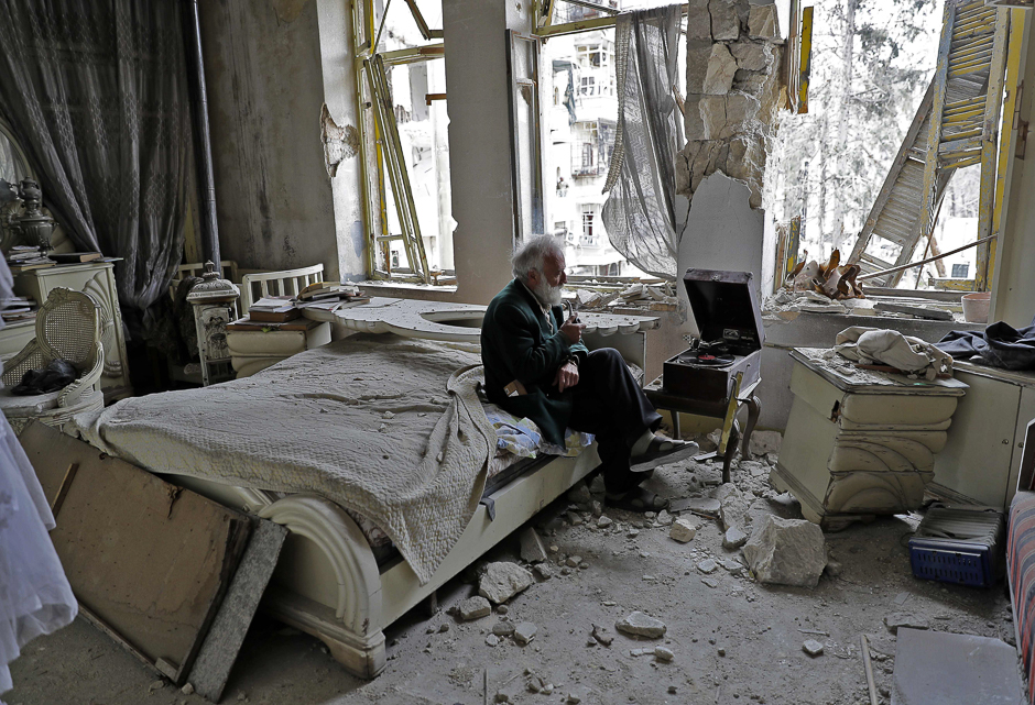 Mohammad Mohiedine Anis, 70, smokes his pipe as he sits in his destroyed bedroom listening to music on his vinyl player in Aleppo's formerly rebel-held al-Shaar neighbourhood. PHOTO: AFP