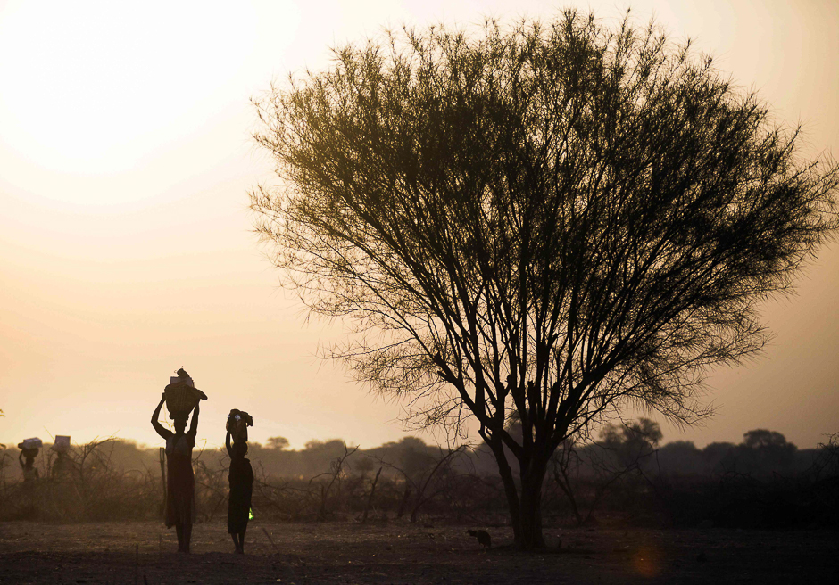 A woman and a girl carry food from a distribution centre in Ngop in South Sudan's Unity State. PHOTO: AFP