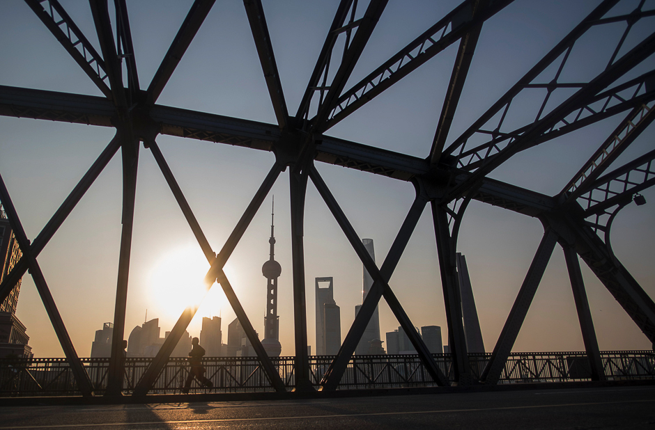 A jogger runs across a bridge on his morning exercise during sunrise at the promenade on the Bund along the Huangpu River, seen against the skyline of the Lujiazui Financial District in Pudong, Shanghai. PHOTO: REUTERS