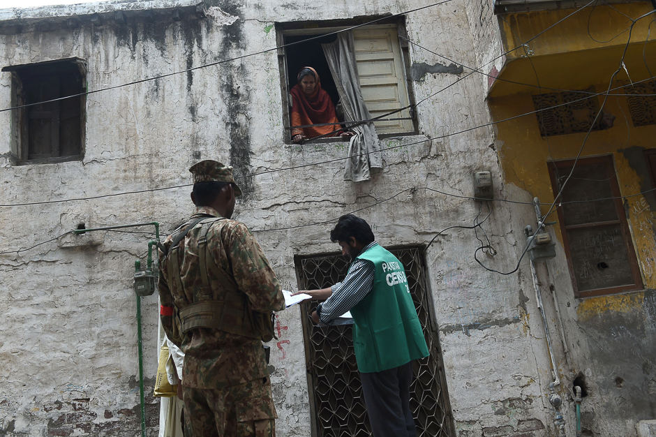 An official from the Pakistan Bureau of Statistics collects information from a resident (top) during a census, as an army soldier stands guard, in Lahore. PHOTO: AFP