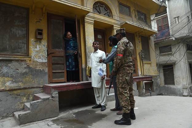 An official from the Pakistan Bureau of Statistics collects information from a resident during a census, as an army soldier stands guard, in Lahore on March 15, 2017. PHOTO: AFP