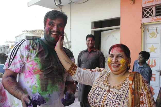 A woman applies colour on a man's face during Holi at Shri Lakshmi Narayan Mandir. PHOTO: AYESHA MIR