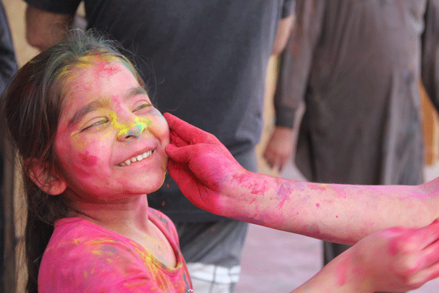 A child smiles as colour is applied to her face during Holi at Shri Lakshmi Narayan Mandir. PHOTO: AYESHA MIR