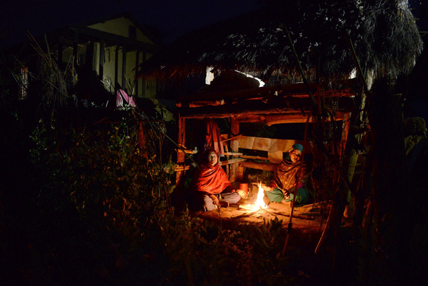 Nepalese women Pabitra Giri (L) and Yum Kumari Giri (R) sit by a fire as they live in a Chhaupadi hut during their menstruation period in Surkhet District, some 520km west of Kathmandu, February 3, 2017. PHOTO: AFP