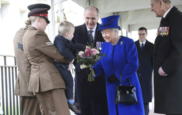 Alfie Lun, 2, is held up by his mother Michelle as he hands a bouquet to Britain's Queen Elizabeth during the unveiling of the new memorial to members of the armed services who served and died in the wars in Iraq and Afghanistan, in London, Britain, March 9, 2017. PHOTO: REUTERS