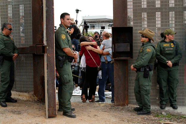 US Border patrol agents stand watch at an open gate on the fence along the Mexico border to allow Delia Valdovinos-Sanchez to embrace Ramona Vargas, as part of Universal Children's Day at the Border Field State Park, California, US on November 19, 2016. PHOTO: REUTERS