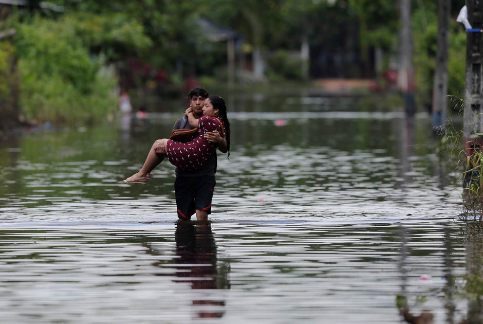 A man carries his wife on a flooded street after heavy rainfall in Milagro, Ecuador. PHOTO: REUTERS