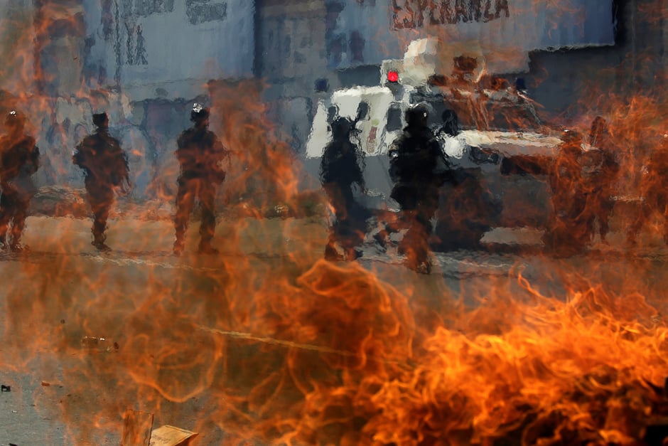 Venezuelan national guards walk behind a burning blockade during clashes with demonstrators during an opposition rally in Caracas, Venezuela. PHOTO: REUTERS