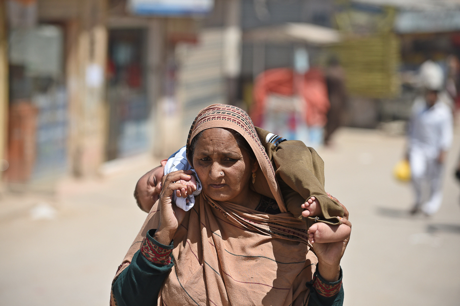 A Pakistani woman carries a child as she visits a market outskirts of Islamabad. PHOTO: AFP