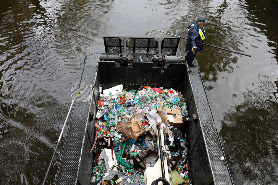 A worker cleans garbage with a boat in the canals of Amsterdam, a day after Kings Day was celebrated. PHOTO: AFP