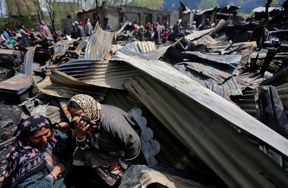 Women weep as they sit around remains of their houses gutted in a fire which broke out in a residential area on Tuesday, in Srinagar. PHOTO: REUTERS