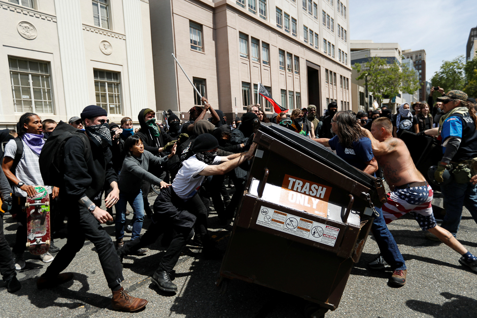 Demonstrators for (R) and against (L) US President Donald Trump push a garbage container toward each other during a rally in Berkeley, California in Berkeley, California, US. PHOTO: REUTERS