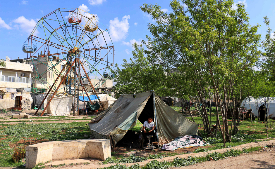 A boy sits outside a tent where a displaced family lives near a makeshift fairground in the city of Azaz, on Syria's northern border with Turkey. PHOTO: AFP