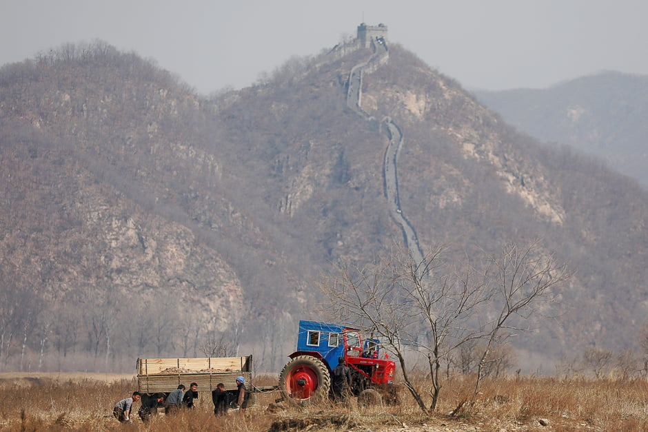 North Korean farmers work in a field as a section of the Great Wall is seen on the Chinese side of the Yalu River, north of the town of Sinuiju in North Korea and Dandong in China's Liaoning province. PHOTO: REUTERS