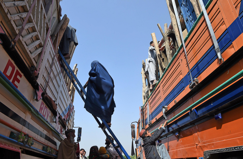 An Afghan refugee woman climbs onto a truck at the United Nations High Commissioner for Refugees (UNHCR) repatriation centre on the outskirts of Peshawar, as they prepare to return to their home country after fleeing civil war and Taliban rule. PHOTO: AFP