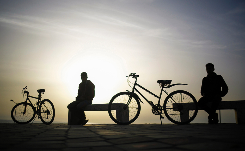Palestinian youths rest on benches next to their bicycles after a ride in Gaza City. PHOTO: AFP