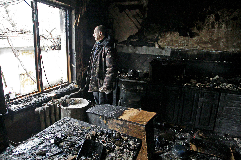 A local resident looks out of a window at his house damaged by shelling, in the rebel-held city of Donetsk, Ukraine. PHOTO: REUTERS