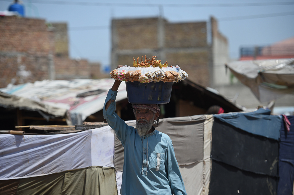A Pakistani snack vendor carries a basket of items for sale as he looks for customers on a street on the outskirts of Islamabad. PHOTO: AFP