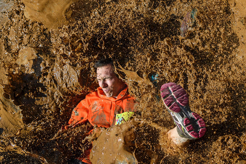 A competitors lands in mud as they take part in the 
