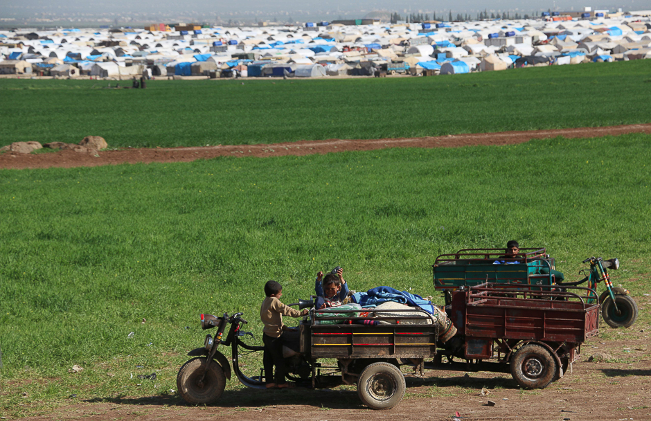 Syrian children play next to vehicles outside the Nour make-shift camp, east of the city of Azaz, on Syria's northern border with Turkey. PHOTO: AFP