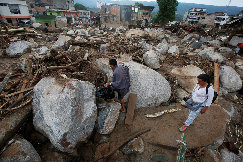 People walk on a street destroyed after flooding and mudslides, caused by heavy rains leading several rivers to overflow, pushing sediment and rocks into buildings and roads, in Mocoa, Colombia. PHOTO: REUTERS