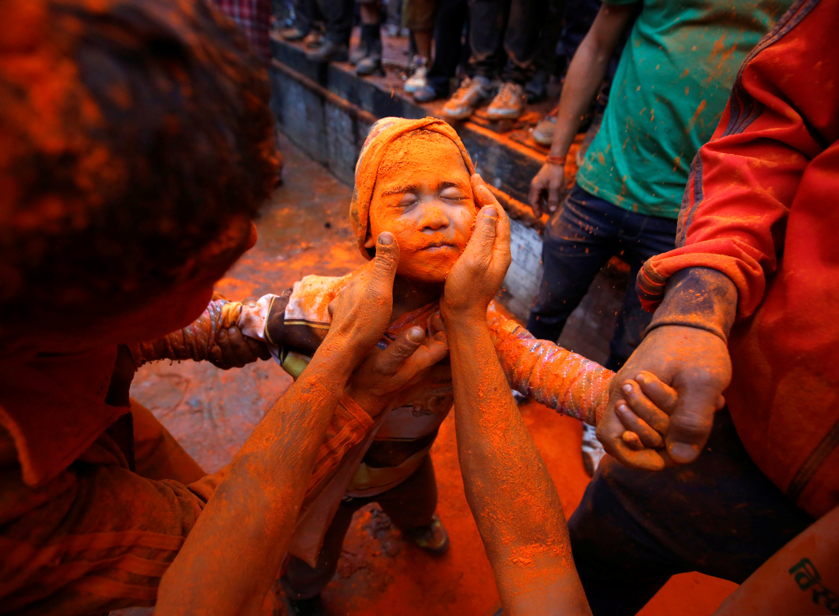A boy gets his face smeared with vermillion powder during 