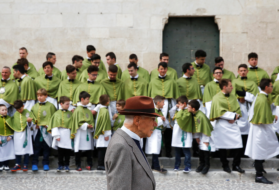 An old man walks past members of the Confraternity of Our Lady of Loreto before other members run across a square carrying the statue of Madonna che Scappa (The Madonna Who Runs) during an Easter Sunday celebration in Sulmona, Italy. PHOTO: REUTERS
