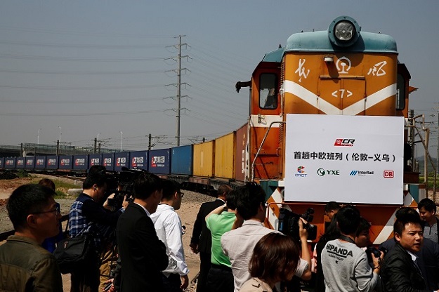  People take pictures as a train carrying containers from London arrives at the freight railway station in Yiwu, Zhejiang province, China, April 29, 2017. The sign at the front of the train reads: 